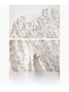 Detail of floral baby romper featuring ruffled collar and resin snap buttons on soft cotton