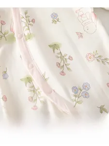 Détail d'une grenouillère pour bébé avec boutons-pression et motifs fleurs lapins