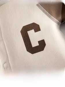 Détail d'un barboteuse pour bébé avec patch lettre C marron et texture tricotée douce