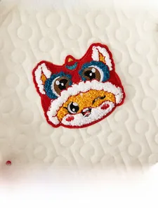 Detail of baby quilted fabric with a traditional Chinese lion dance towel embroidery patch