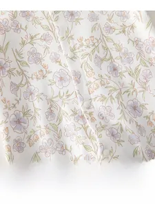 Detailed macro view of baby romper featuring purple floral print and snap buttons