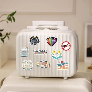 Close-up of colorful anxiety awareness stickers applied on a white suitcase surface