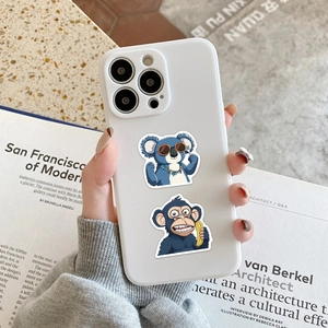 White iPhone case with blue koala and monkey stickers held in a hand over a desk