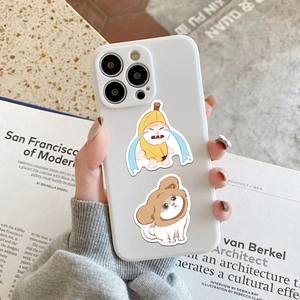 Close-up of white iPhone case featuring cute cartoon cats on a minimalist book background