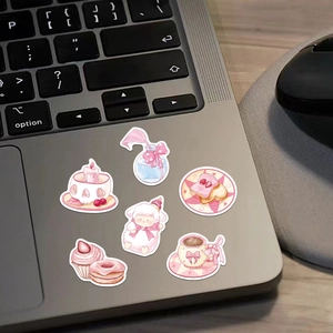Pink aesthetic stickers on laptop keyboard including strawberry cake and ribbon patterns