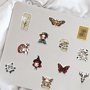 Set of 50 vintage gothic stickers with skulls and moths on a gray laptop surface