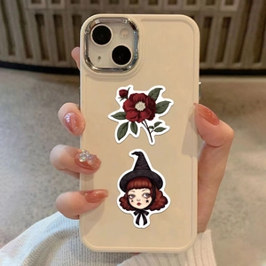 Detail of vintage gothic flower and cartoon witch stickers on a beige phone case surface