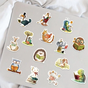 Flat lay of bookish animal stickers displayed on a silver laptop with white fabric decor