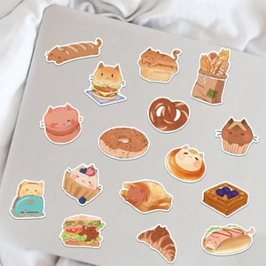 Close-up of cute cartoon cat-themed pastry stickers on a laptop surface for decoration