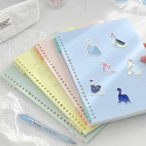 Close-up of four colorful spiral notebooks with cute cartoon dinosaur stickers on a desk