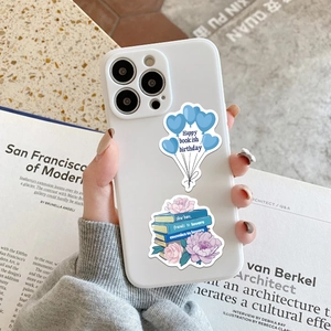 Detailed view of white bookish phone case with balloon and stack of books floral design