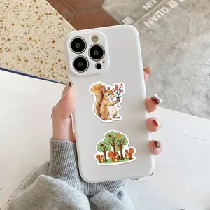 Close-up of cute squirrel stickers on a white phone case set against a cozy background