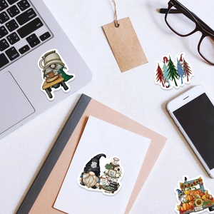 Close-up of cute cartoon gnome stickers on a desk with laptop and stationery props