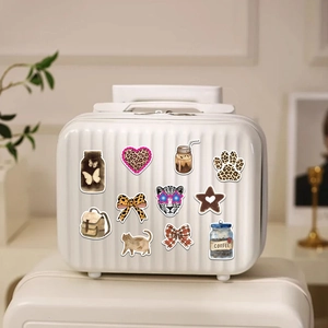 Detail showing various leopard pattern stickers applied on a white striped suitcase surface