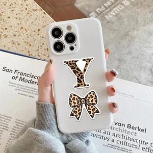 Detail of white iPhone case with leopard print, letter Y, and bow on a magazine