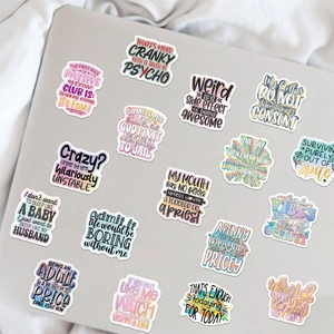 Close-up of assorted sarcastic cartoon quote stickers on a gray laptop surface