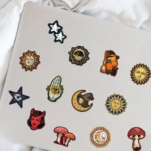 Vintage occult stickers with sun, moon, and mystic eye motifs on a gray laptop surface