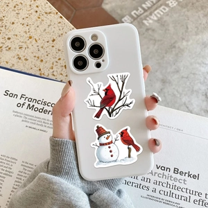White iPhone case featuring a winter cardinal and snowman illustration on a desk