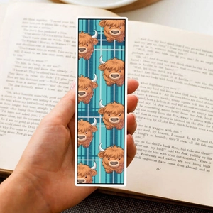 Close-up of a cute cartoon highland cow bookmark held over an open book for reading