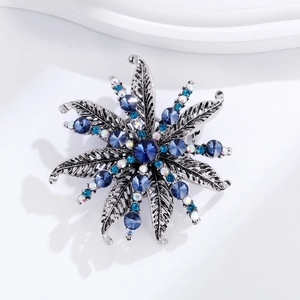 Macro detail of vintage floral brooch featuring blue rhinestones and antique silver finish
