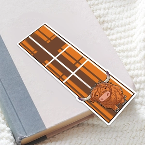 Scottish plaid bookmark featuring a cute cartoon highland cow resting on a hardcover book