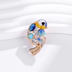 Macro d'une broche oiseau en émail coloré avec strass bleus et alliage doré fin