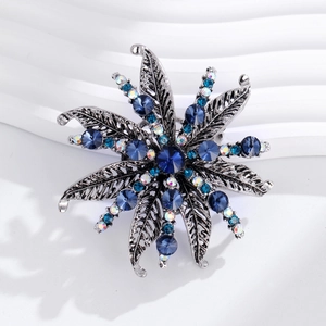Vintage floral rhinestone brooch with blue stones in a silver sunburst pattern
