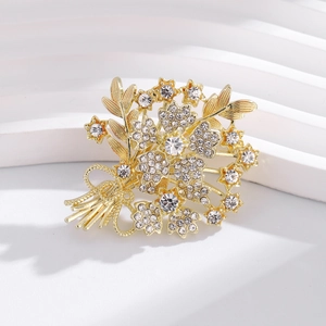 Elegant gold bouquet brooch with shimmering crystal rhinestones on minimalist stand