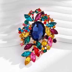 Macro shot of colorful cluster brooch with deep blue center stone and gold-plated details