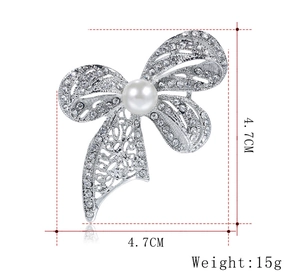 Detail view of crystal bow brooch with white pearl measuring 4.7cm by 4.7cm