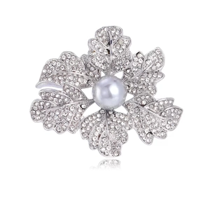 Détail d'une broche fleur argentée avec strass blancs et une grande perle grise centrale