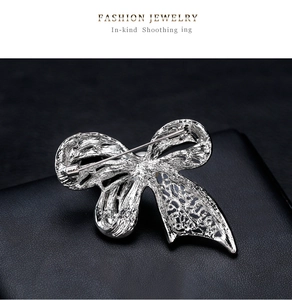 Detail view of the silver bow brooch back with secure pin clasp on black leather