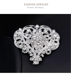 Macro view showing detailed white rhinestone heart brooch on black leather background