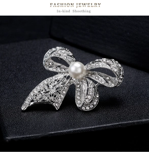 Detail view of silver bow brooch with sparkling crystals and a white round pearl