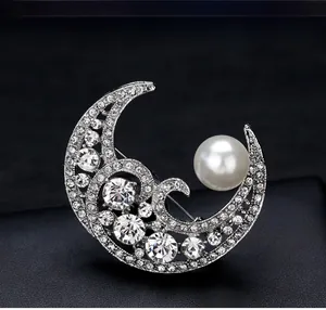 Detailed close-up of a crescent moon brooch with white rhinestones and a large pearl