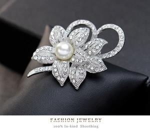 Macro view of flower brooch with white pearl and rhinestone detailing on black leather