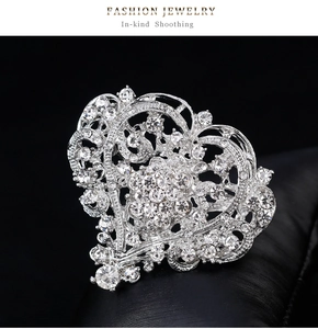 Close-up of heart-shaped silver brooch with intricate crystal pavé detailing on black backdrop
