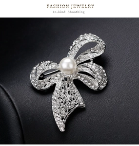 Macro shot of bowknot crystal brooch with white pearl inlay and silver-plated finish
