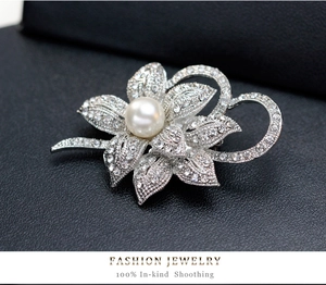 Macro shot of silver flower brooch with sparkling rhinestones and a white pearl accent