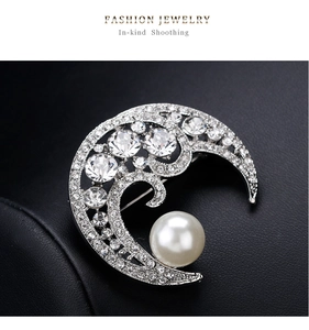 Detailed view of silver moon brooch with pavé rhinestones and a large white round pearl
