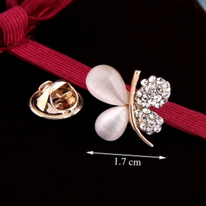 Detail view of a golden butterfly brooch with opal wings and rhinestones on red ribbon