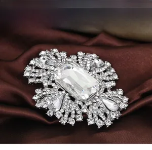 Détail d'une broche de luxe en cristal bleu roi avec pierre taille émeraude sur satin