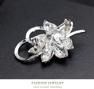 Detail view of the secure pin clasp on a silver flower brooch with metal texture