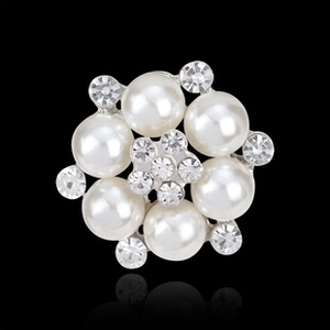 Macro view of a silver-plated pearl flower brooch featuring rhinestones on black background