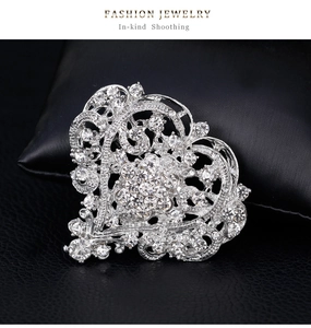 Macro detail of silver heart brooch with sparkling white rhinestones and hollow design