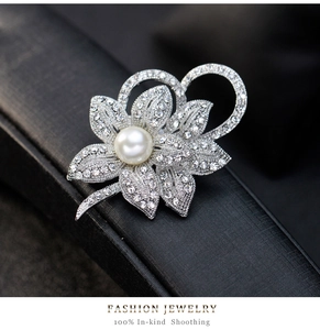 Close-up of elegant silver flower brooch with white pearl and sparkling crystals