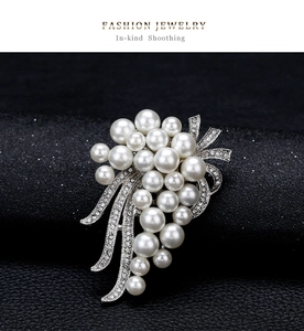 Detailed close-up of a vintage pearl bouquet brooch with sparkling rhinestones on black