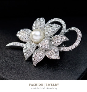 Detailed macro view of a silver flower brooch with white pearl and sparkling crystals