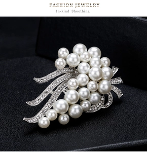 Macro detail of bouquet brooch featuring white pearls and rhinestone-paved silver leaves