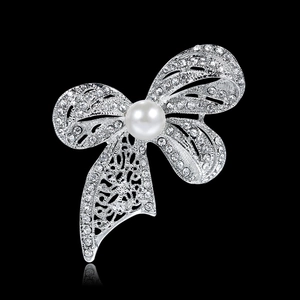 Elegant silver bow brooch with shimmering white crystals and a centered pearl on black